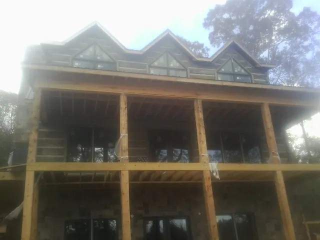 Dormers and porch framing on a large log home under construction — Roof Coating work by our crew in Manhattan Beach