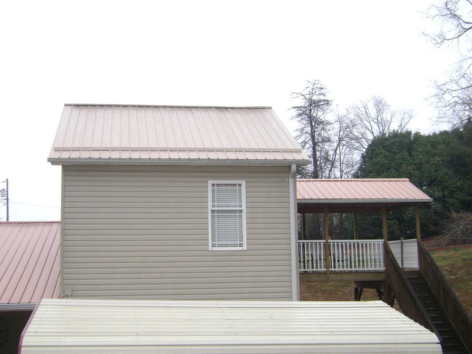 Tan metal roofs on a two story addition and attached porch, from a Roof Replacement job in Manhattan Beach