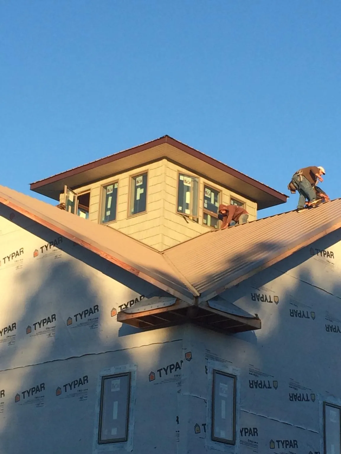 Roofers working around a rooftop cupola on a new metal roof at sunset — Roof Waterproofing in Manhattan Beach by Roofing Brothers